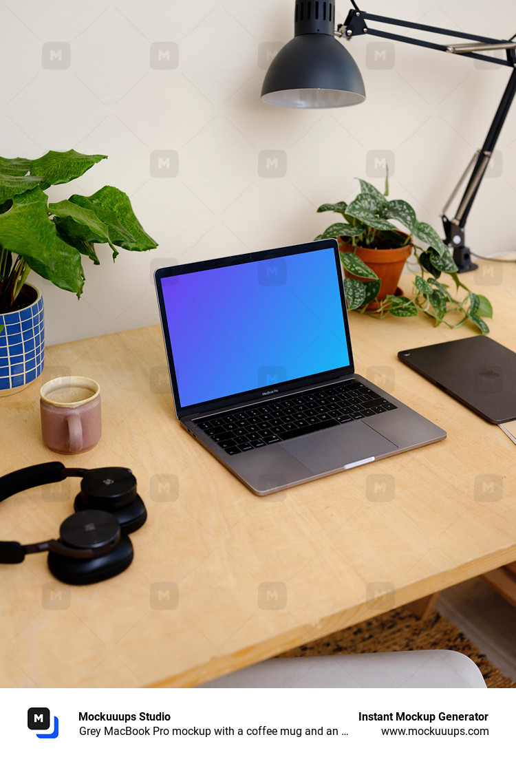 Grey MacBook Pro mockup with a coffee mug and an iPad at the side.