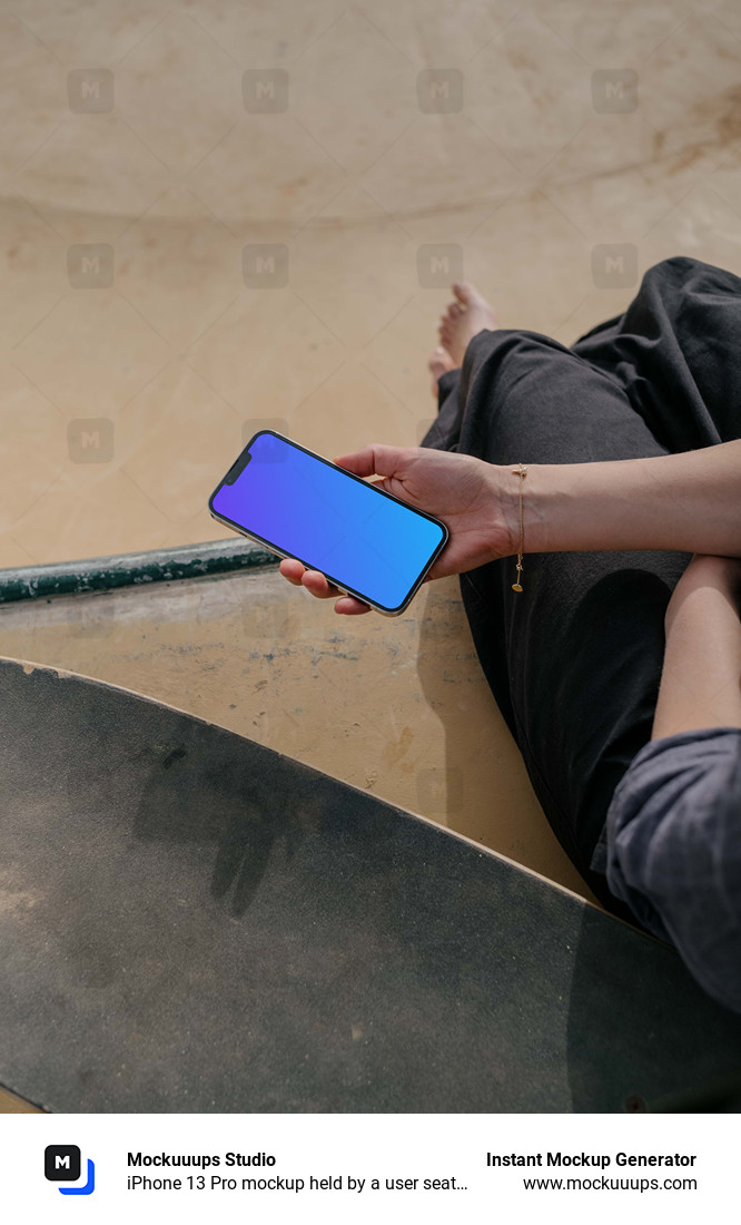  iPhone 13 Pro mockup held by a user seated next to a skateboard