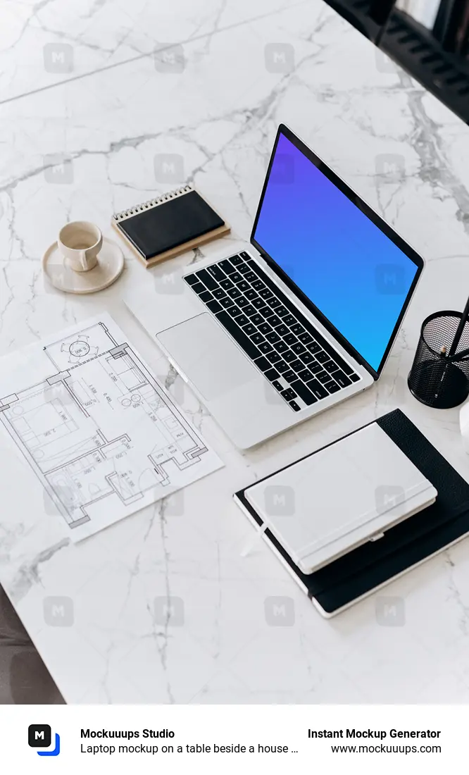 Laptop mockup on a table beside a house plan