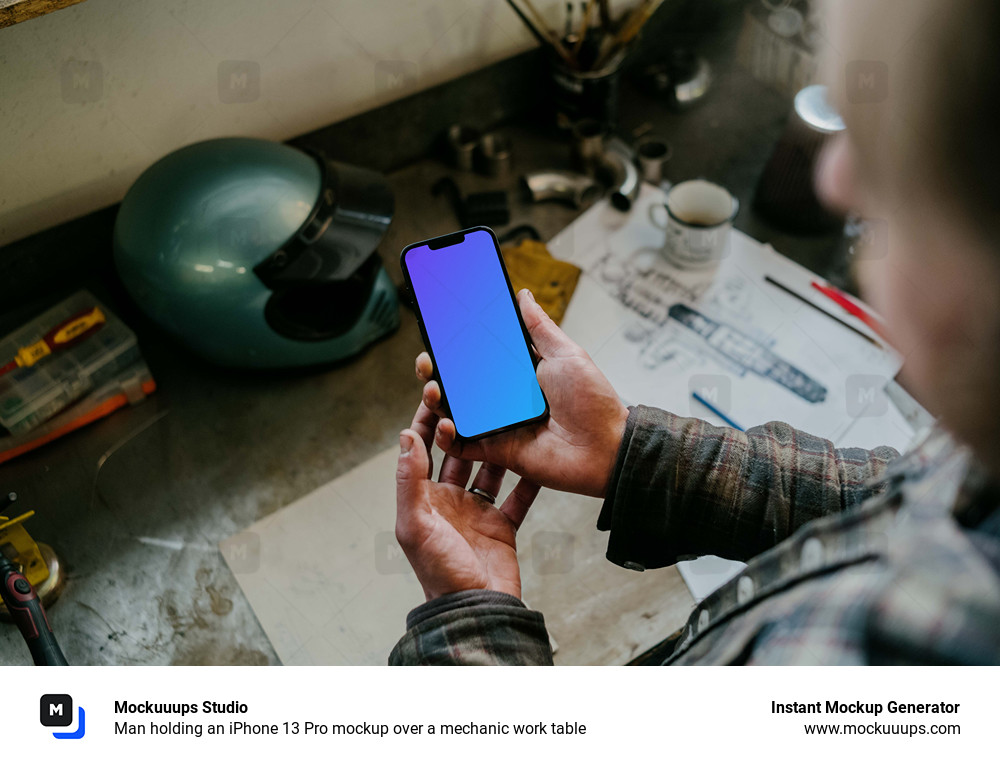 Man holding an iPhone 13 Pro mockup over a mechanic work table
