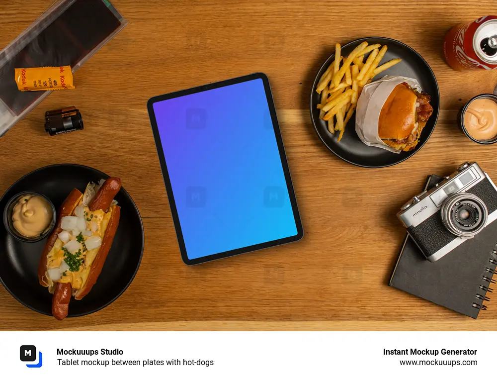 Tablet mockup between plates with hot-dogs