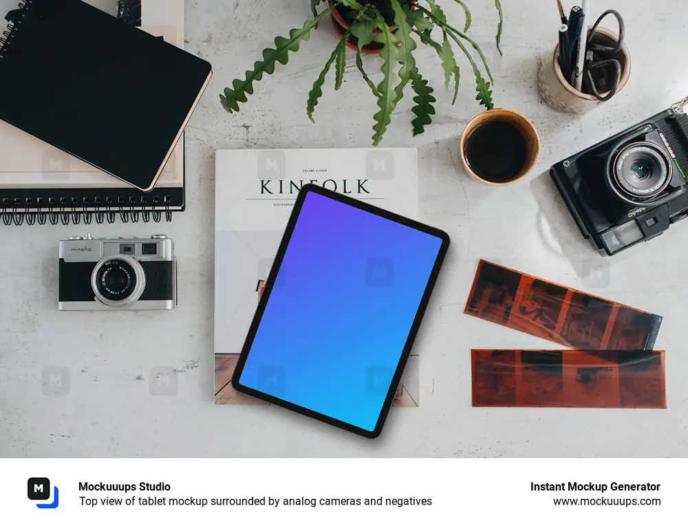 Top view of tablet mockup surrounded by analog cameras and negatives