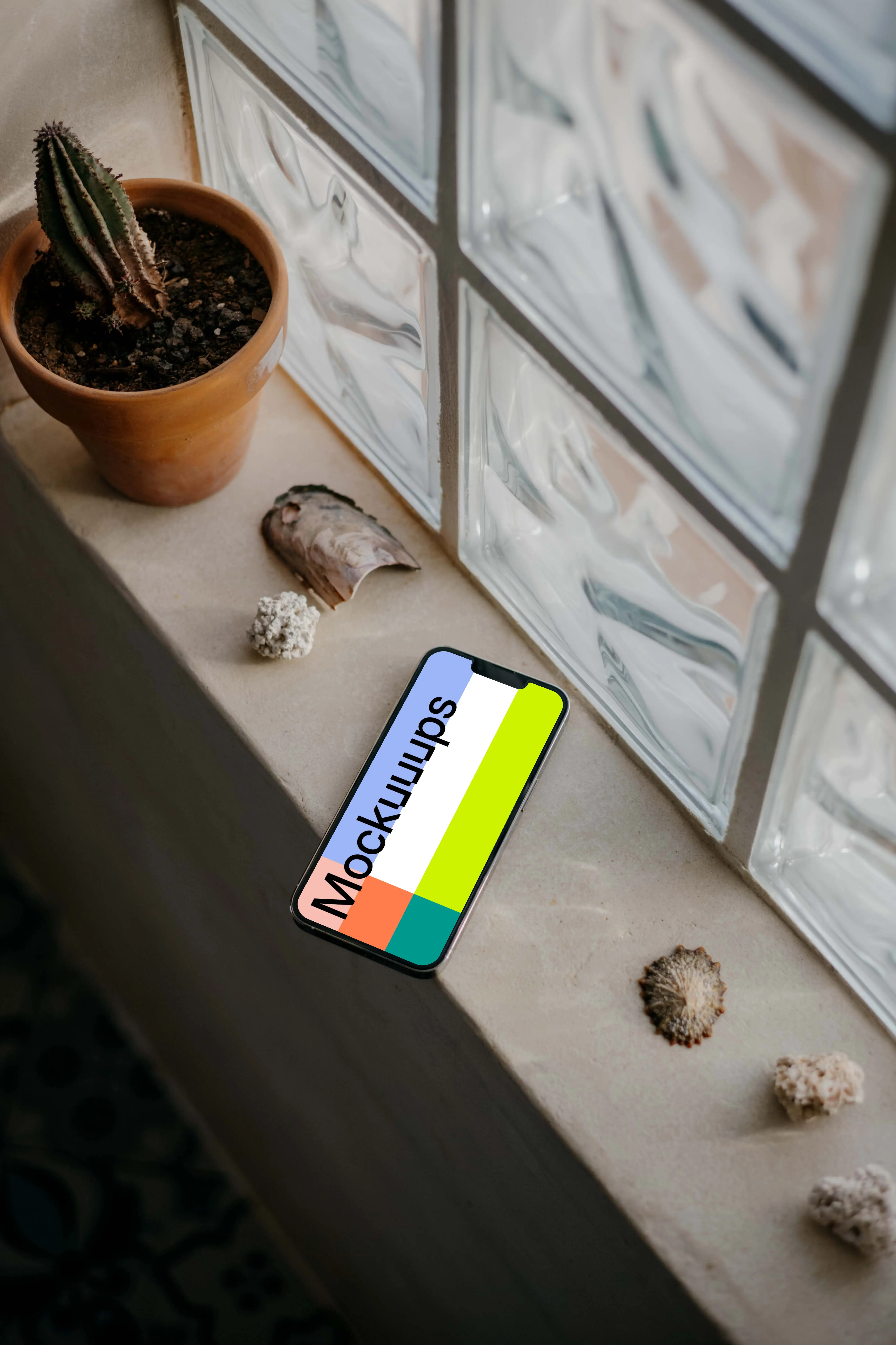 iPhone 13 Pro mockup by a window beside some seashells