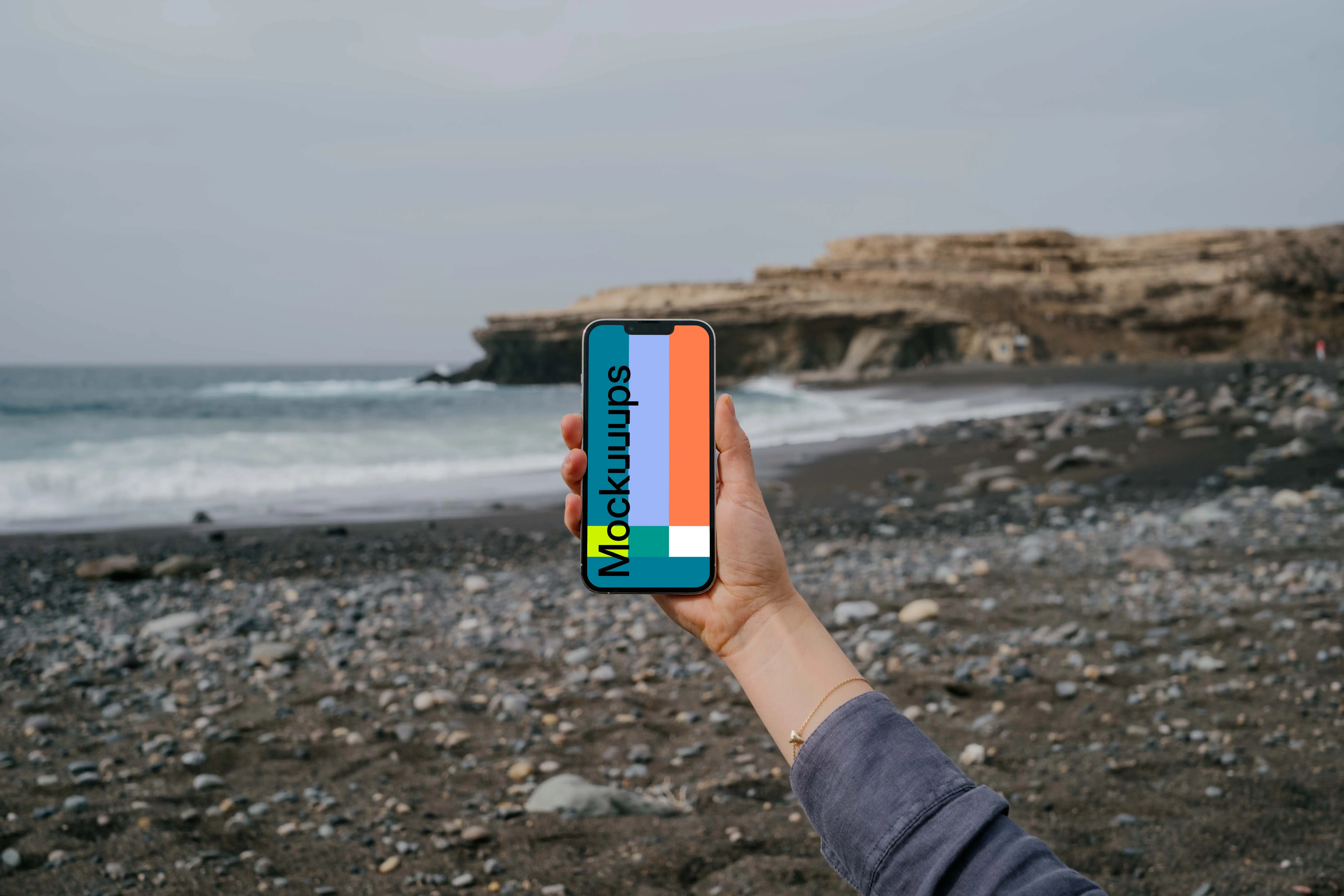 iPhone 13 Pro mockup held by a user against the ocean
