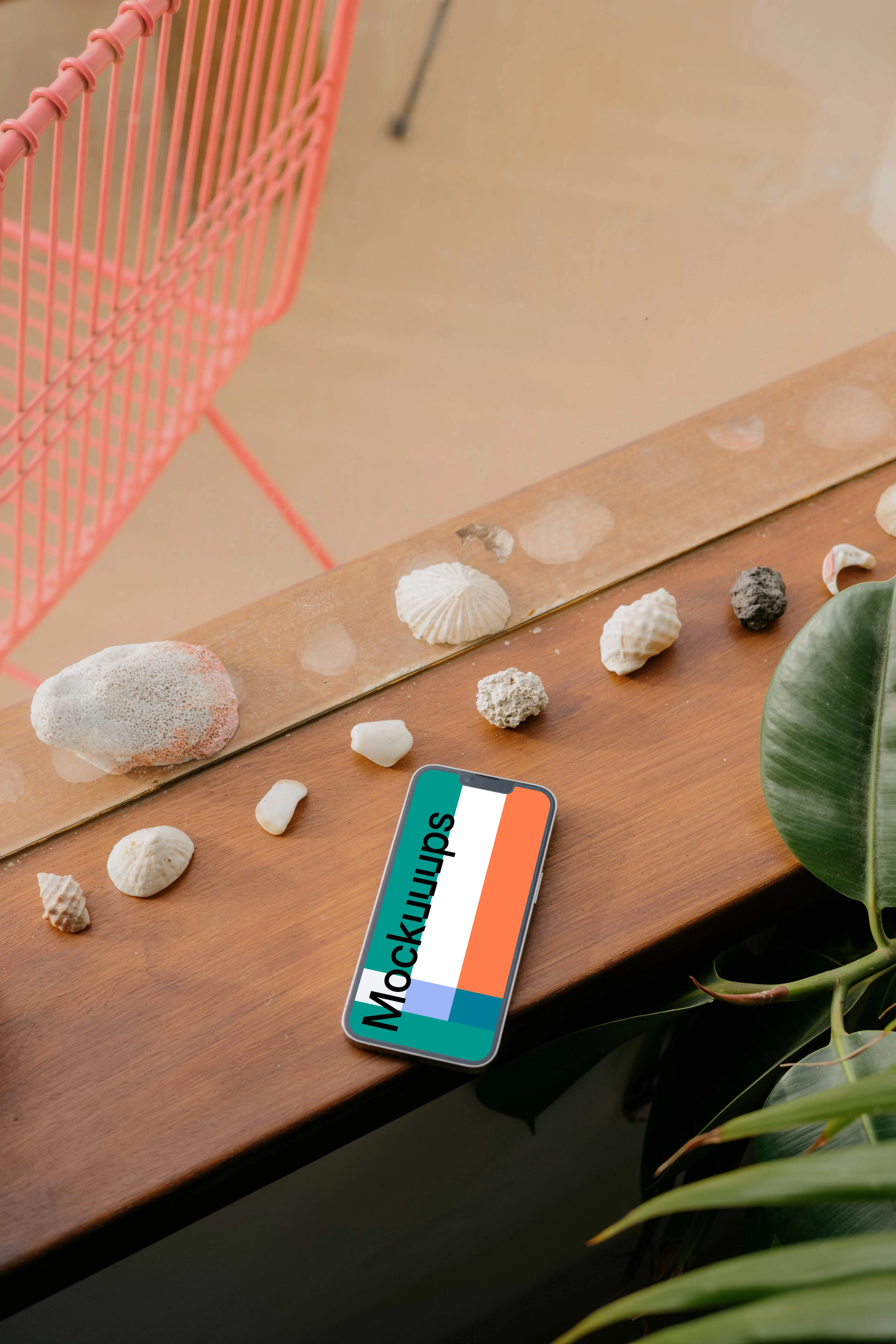 iPhone 13 Pro mockup on a wooden table next to seashells