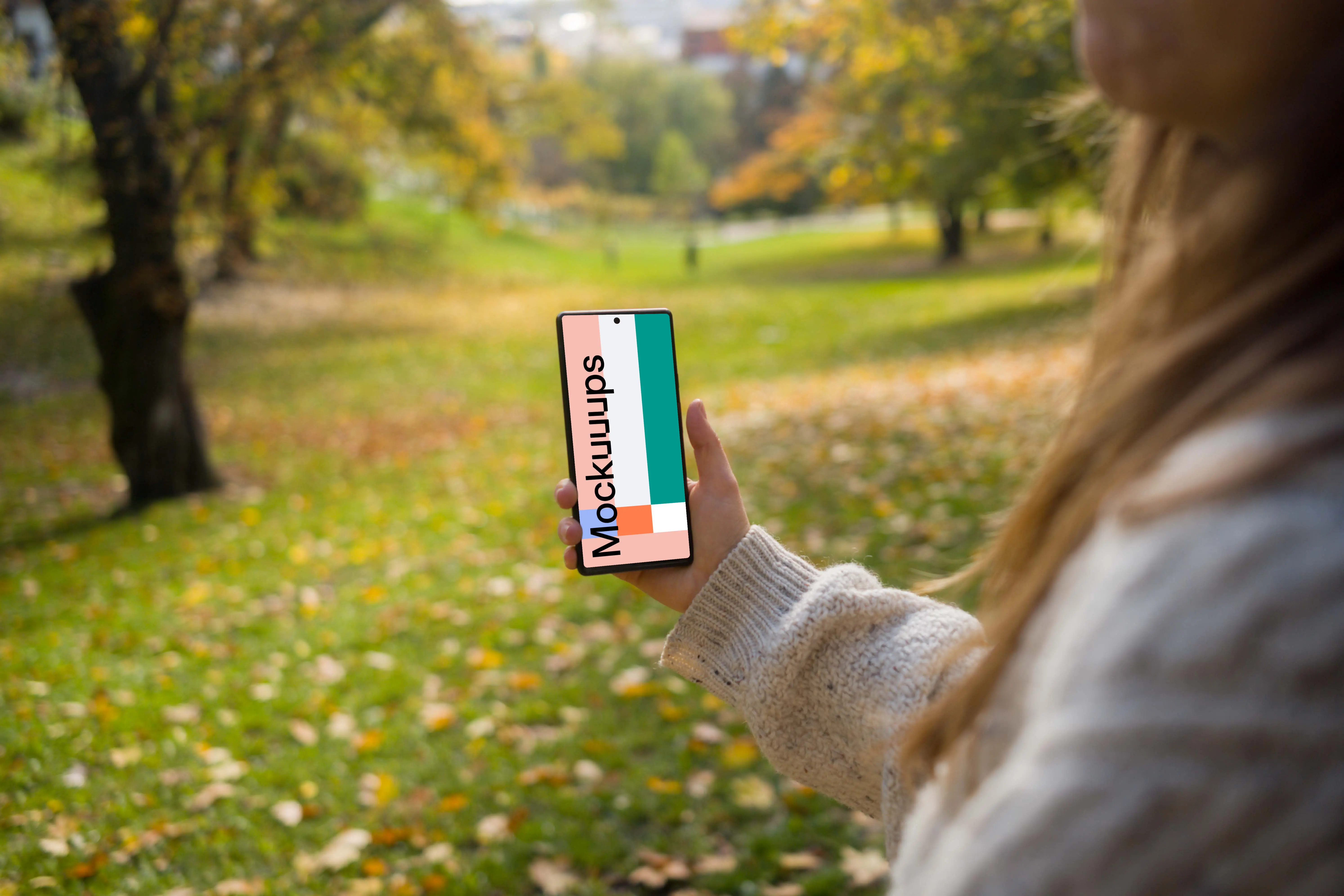 Woman hand holding a phone mockup in the autumn season