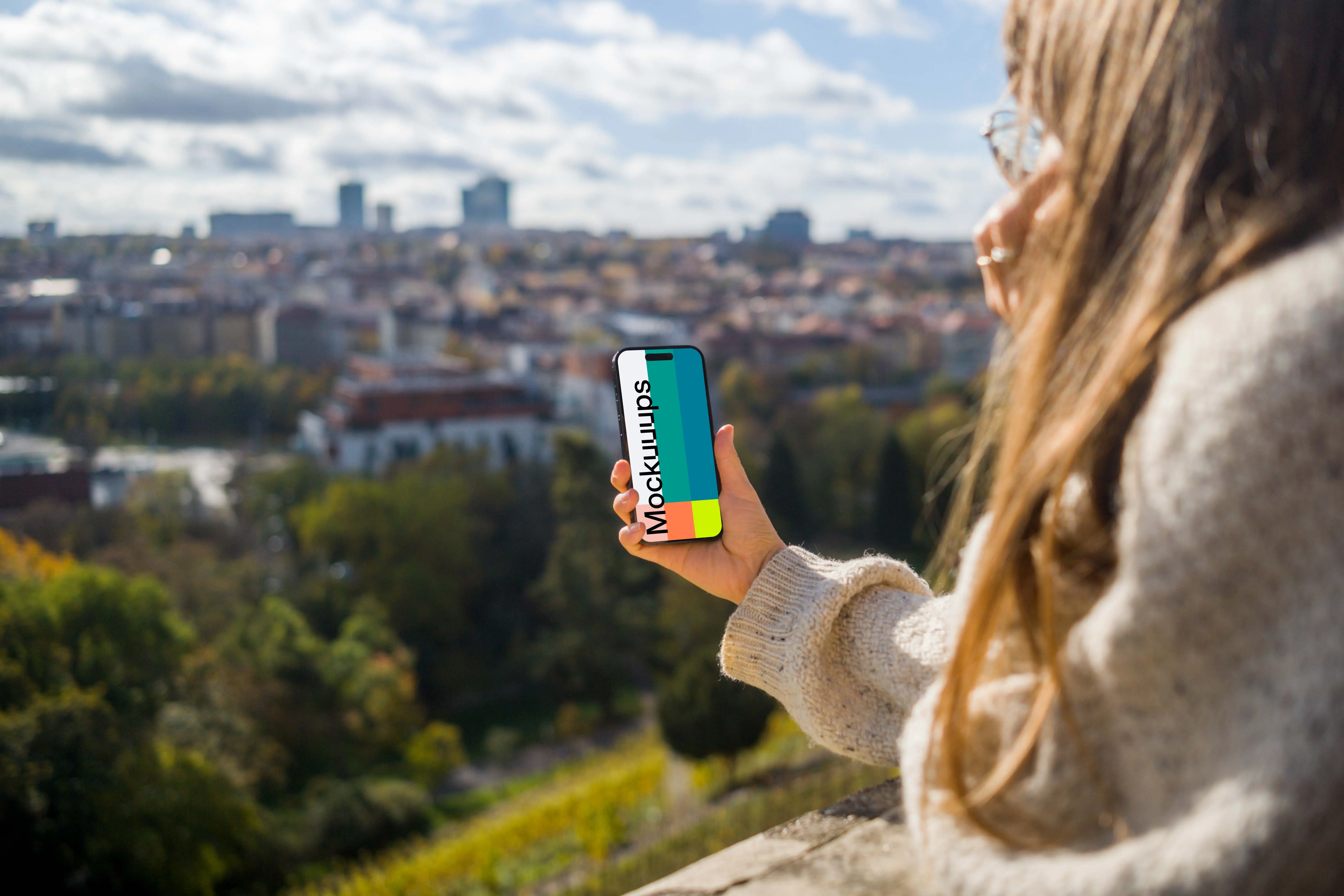 Woman hand holding an iPhone with city view mockup