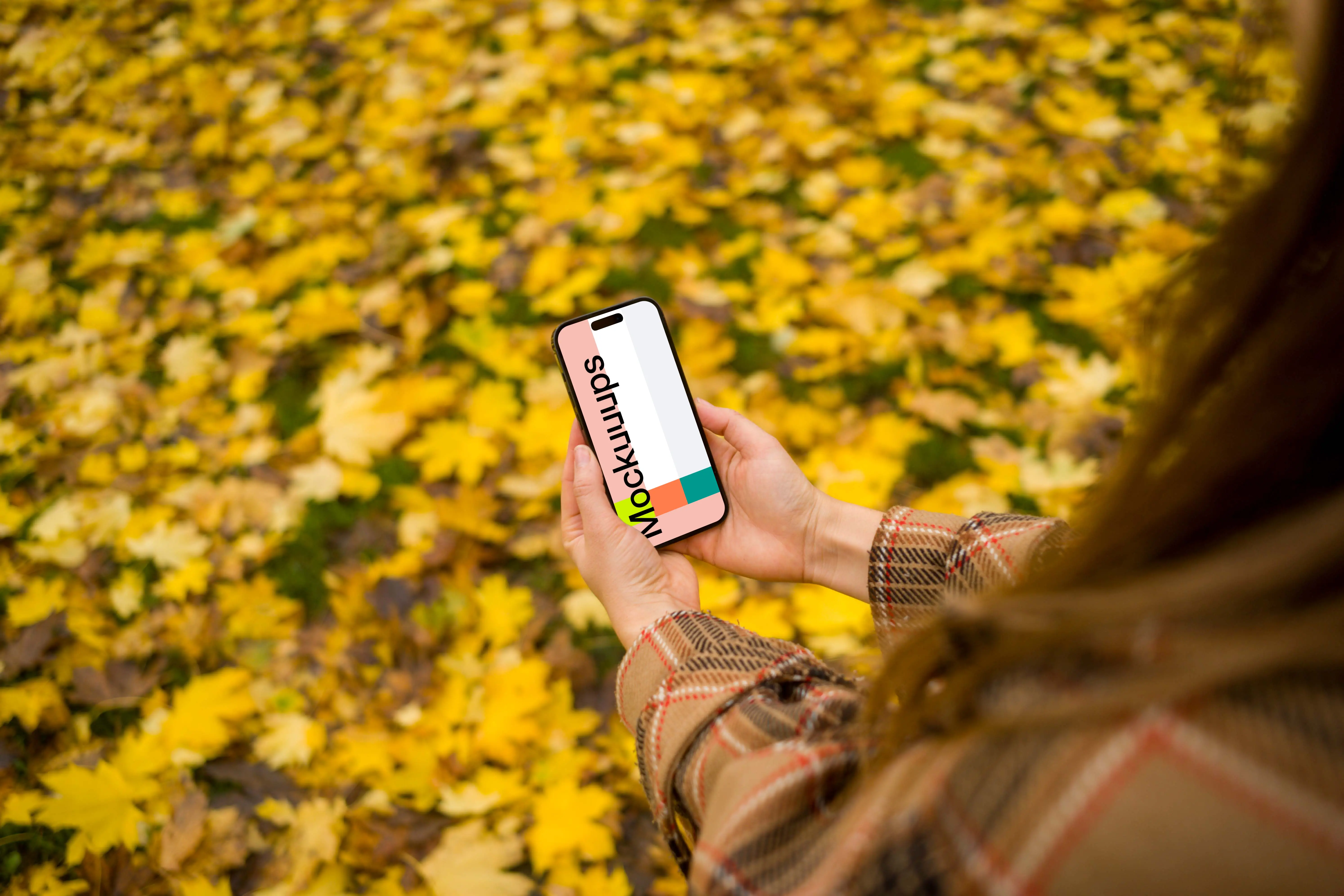Woman hands holding an iPhone 14 Pro in autumn theme mockup