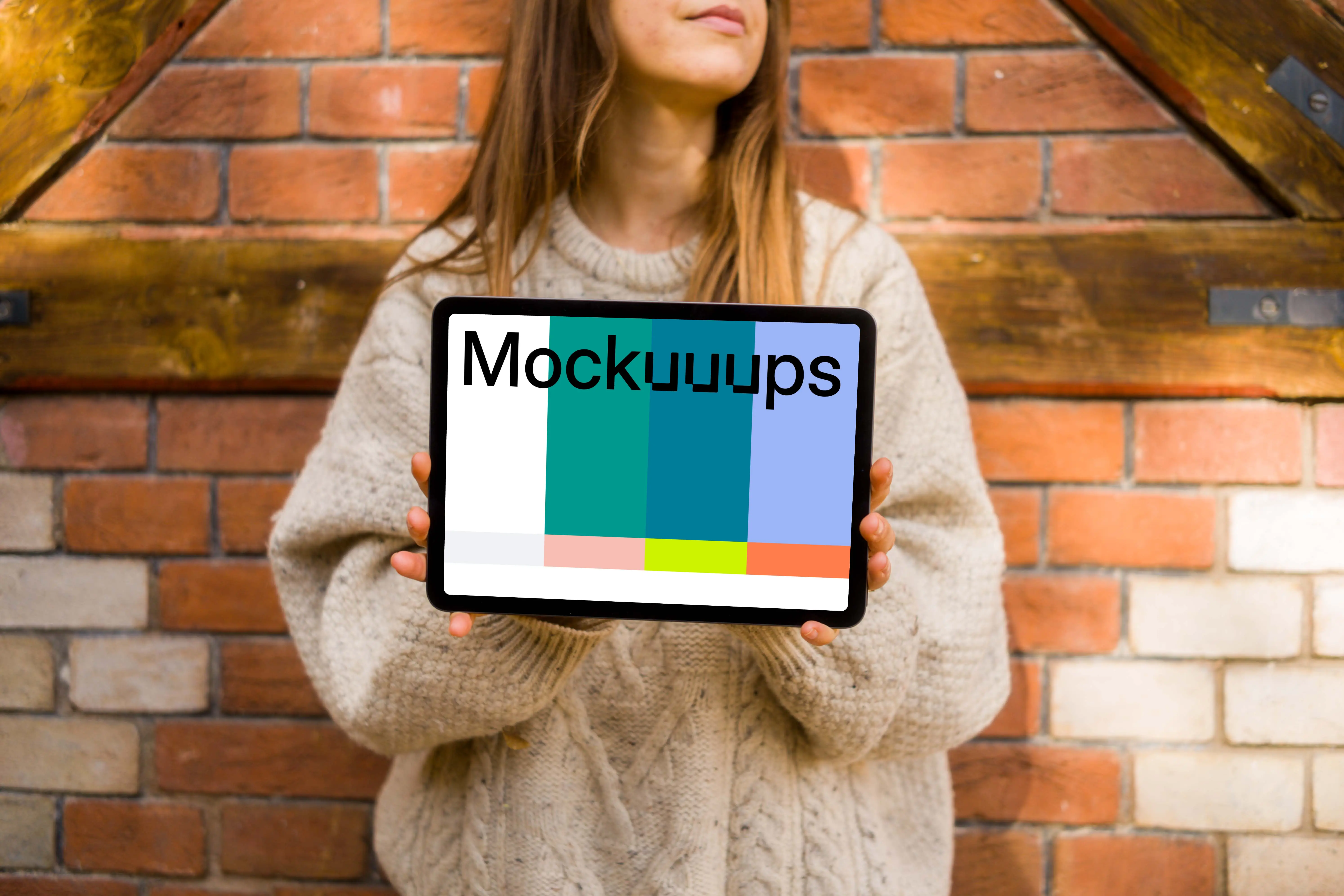 Woman holding an iPad in front of brickwall mockup
