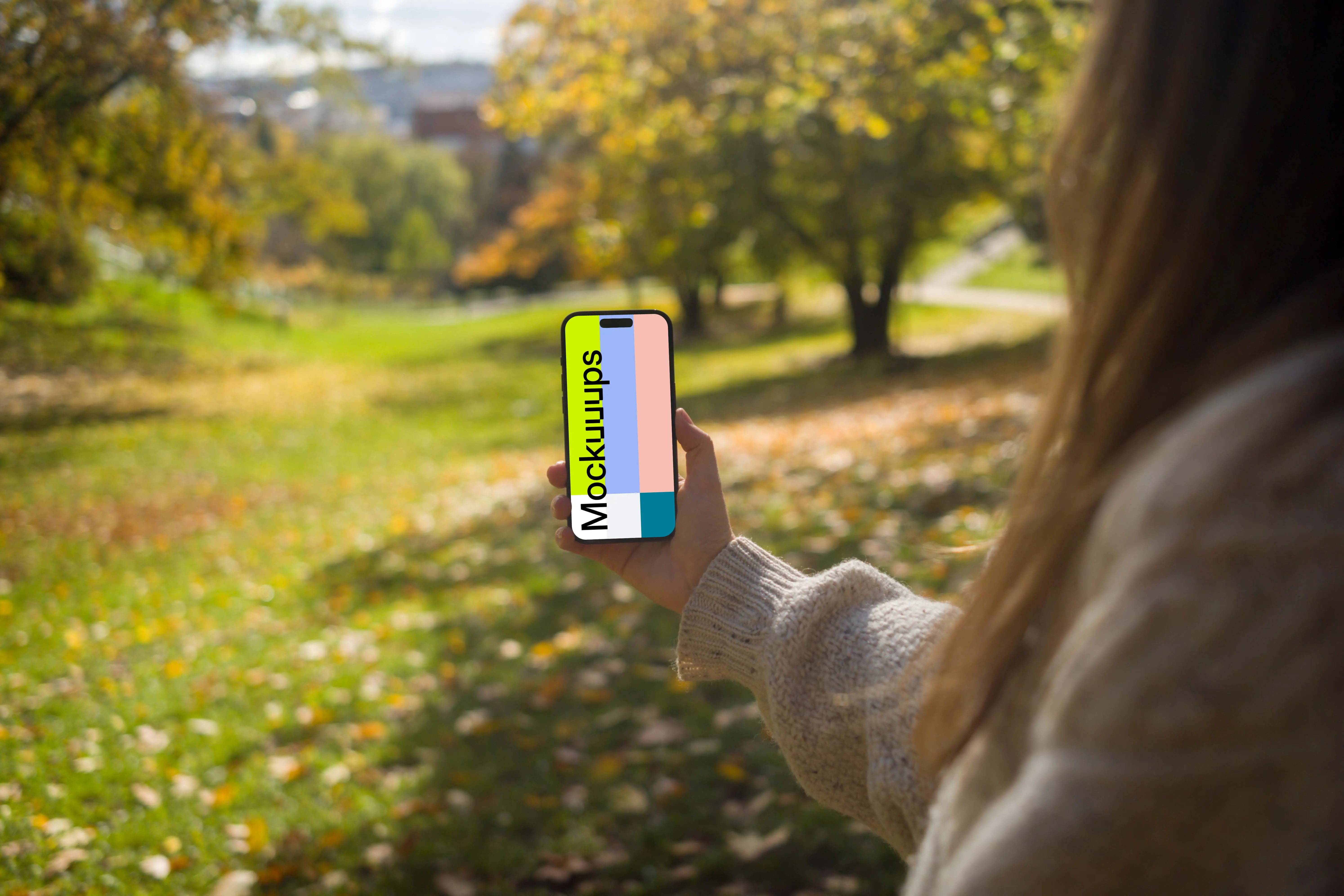 Woman holding an iPhone 14 Pro in nature mockup