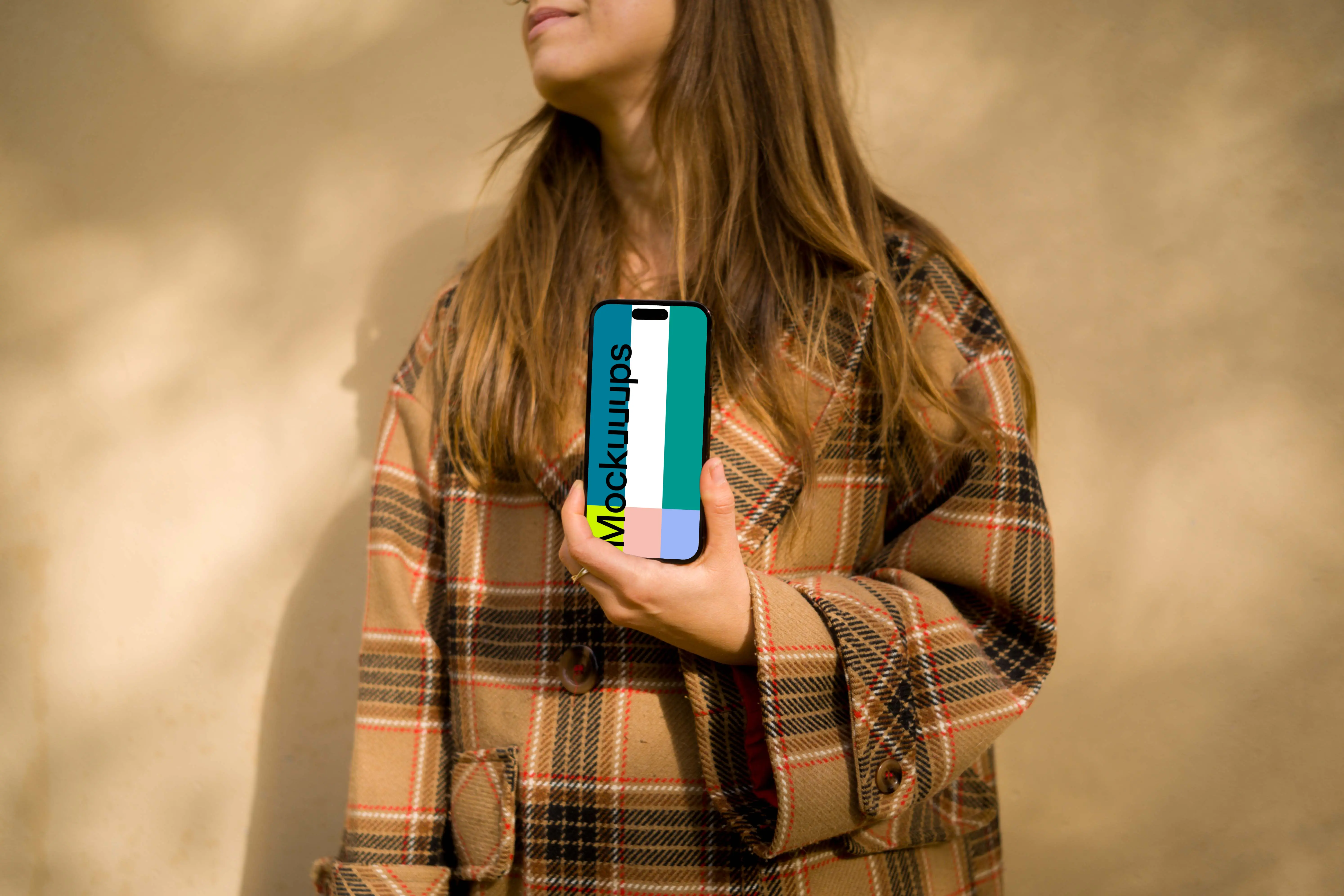 Woman in coat holding an iPhone 14 Pro mockup