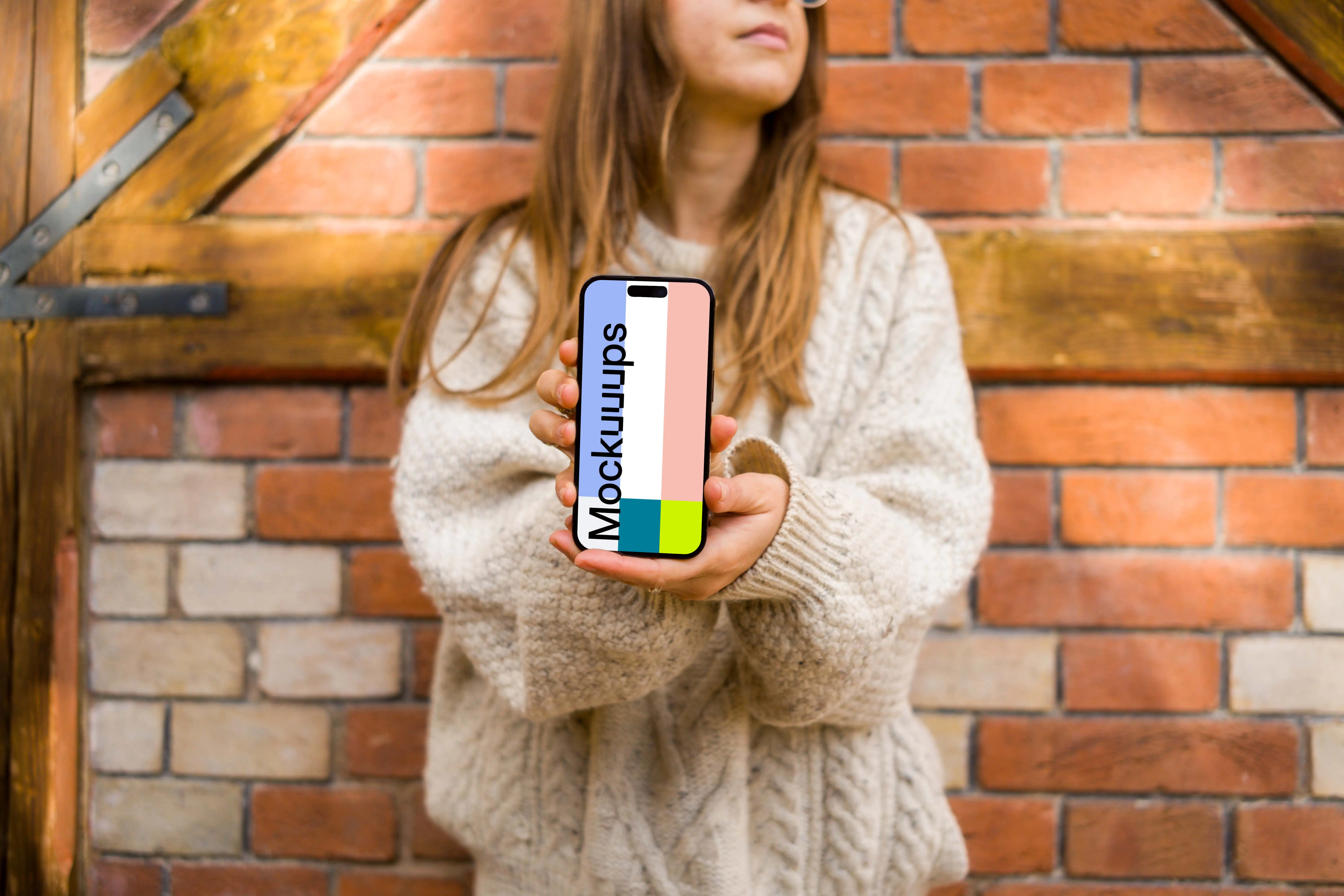 Woman in sweater holding an iPhone 14 Pro mockup