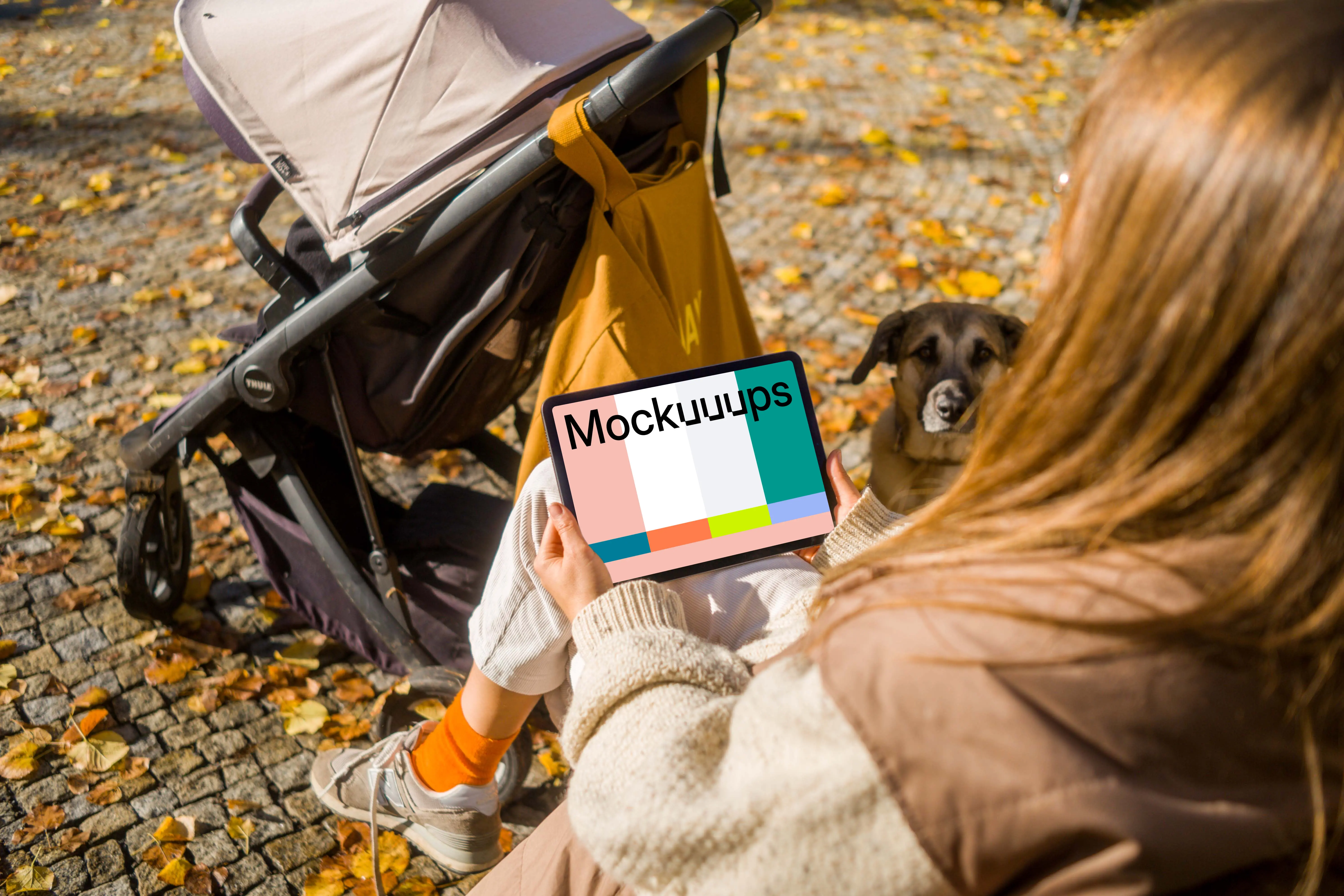 Woman sitting and holding an iPad Air in autumn themed park mockup