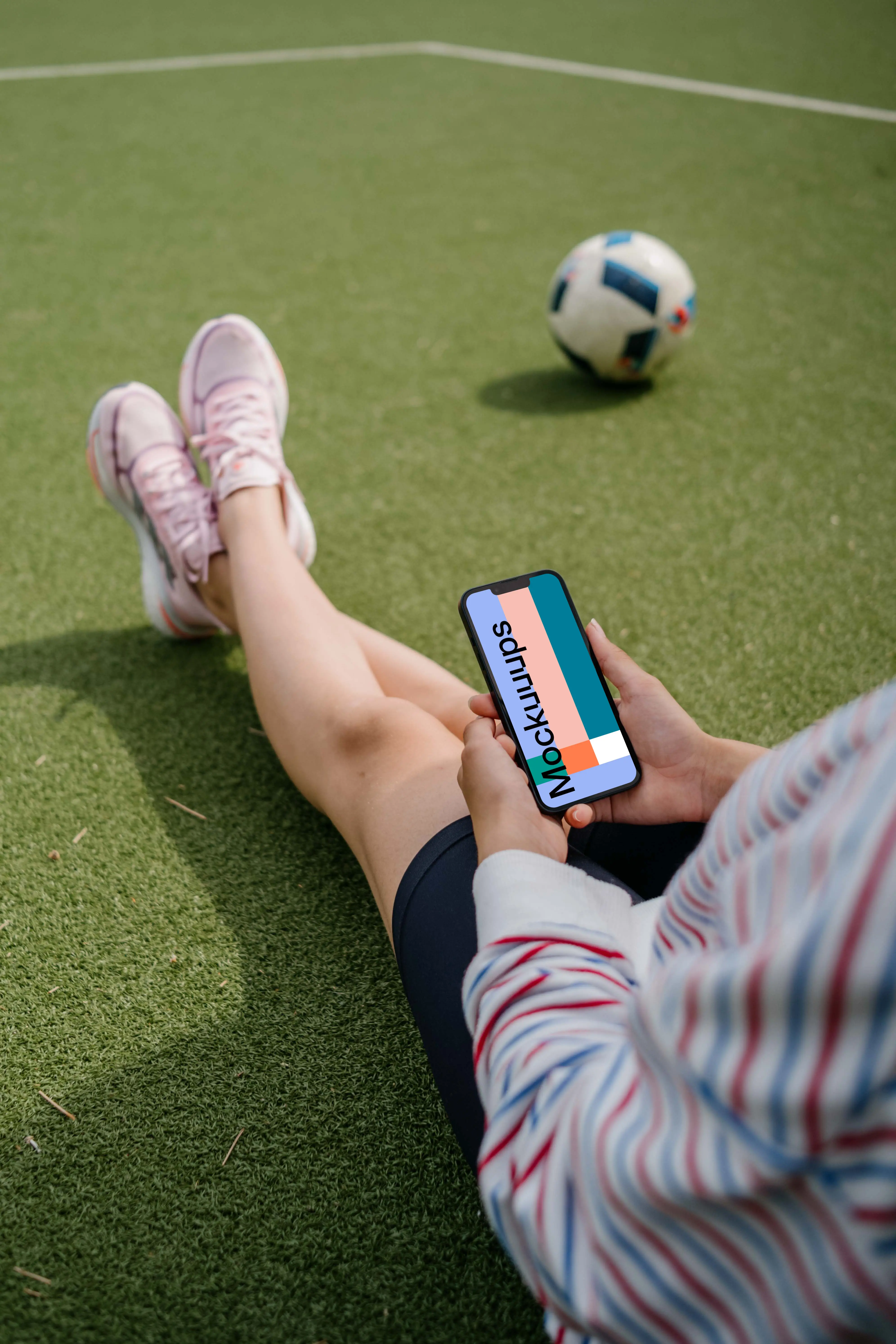 Young woman holding a smartphone mockup on a grass