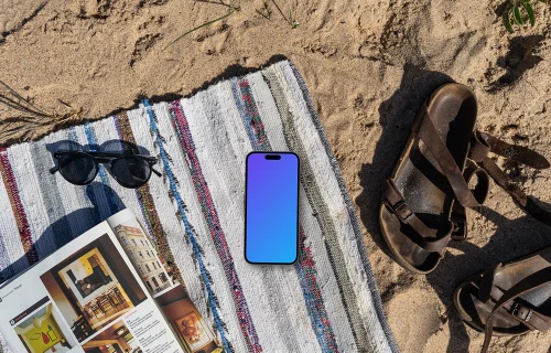 A smartphone mockup laying on a blanket in the sand