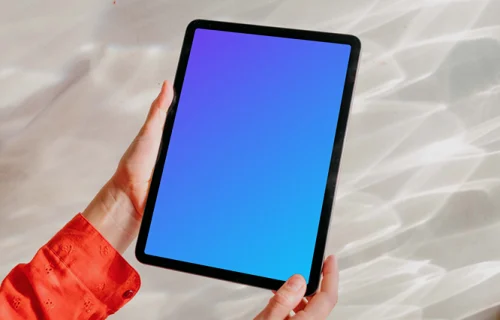 iPad Air mockup held by user against a bright silver background 