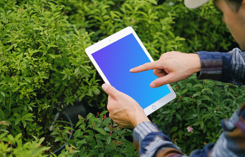 iPad Mini mockup held by a user in a garden 