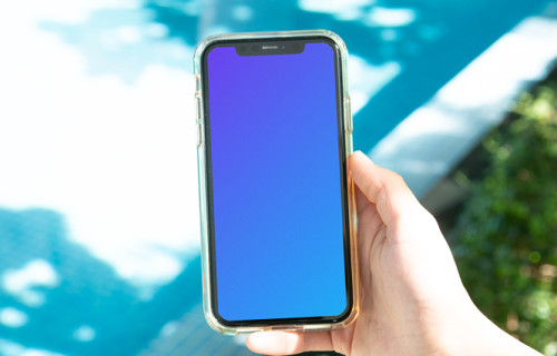 iPhone mockup held by user beside a swimming pool