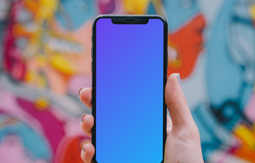 iPhone mockup held in front of graffiti