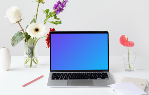 MacBook mockup on a table with flowers by the side