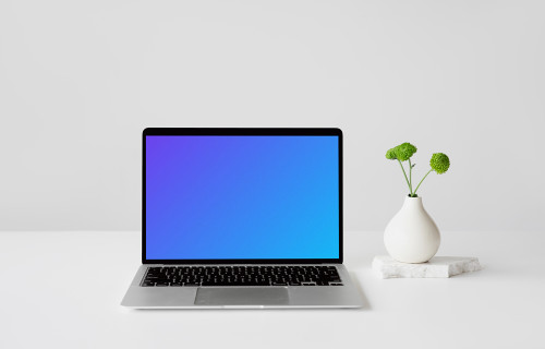 MacBook mockup on a white table with a fancy vase at the side