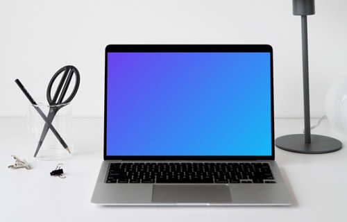 MacBook mockup on a white table with black table lamp at the side