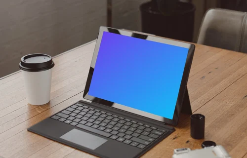 Black Microsoft Surface laptop mockup on a table beside a cup of coffee 