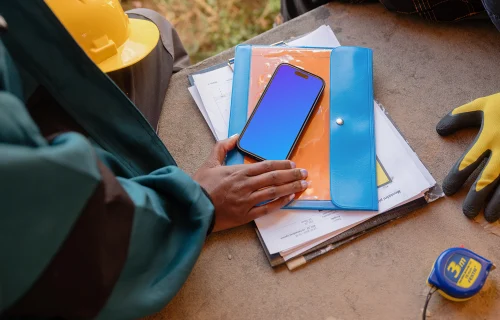 Designer on the construction site with an iPhone 15 Pro mockup