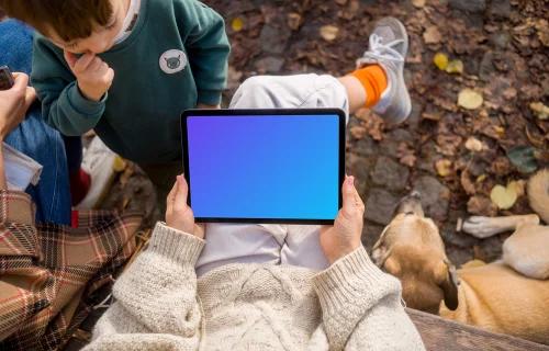 Manos femeninas sosteniendo un iPad Air en otoño mockup