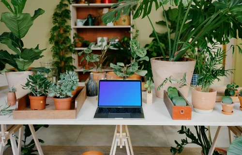 MacBook Pro cinza Mockup em uma mesa branca em meio a vasos de plantas