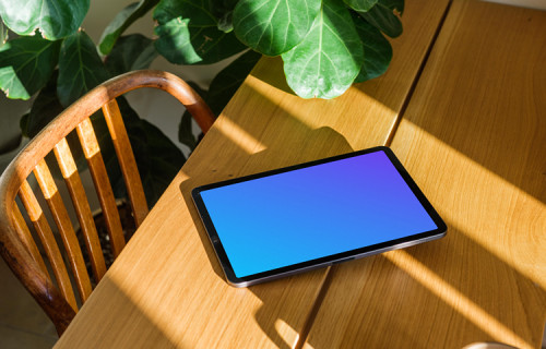 iPad Air mockup on a wooden table beside a plant