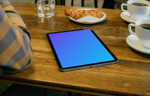 iPad mockup in front of a user beside a croissant