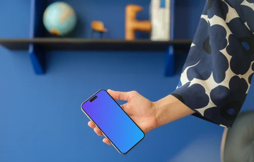 iPhone 15 Pro mockup in a woman's hand against a modern blue wall