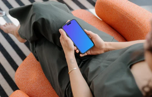 iPhone 15 Pro mockup in a woman's hand on a cozy couch