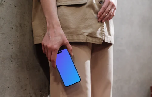 iPhone 16 mockup held by a person against a concrete wall