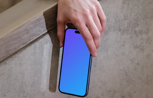 iPhone 16 mockup held by hand against concrete