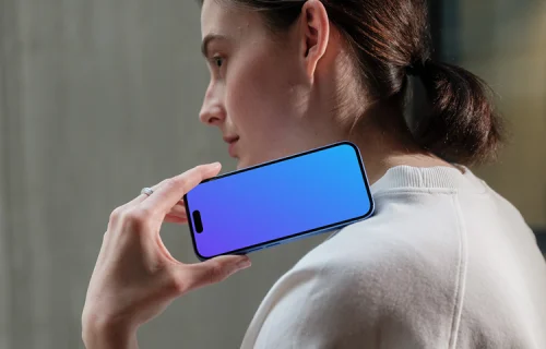 iPhone 16 mockup held by woman near concrete wall