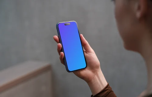 iPhone 16 mockup in a woman's hand with concrete backdrop