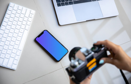 iPhone mockup on a table with a Macbook at the side