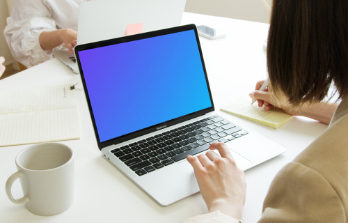 Lady using a MacBook Pro mockup and writing in a notepad