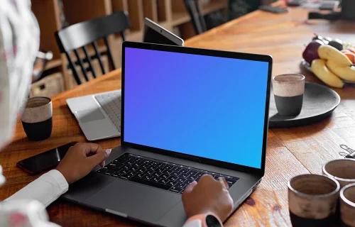 MacBook Air mockup in use by a lady with coffee mugs at the side 