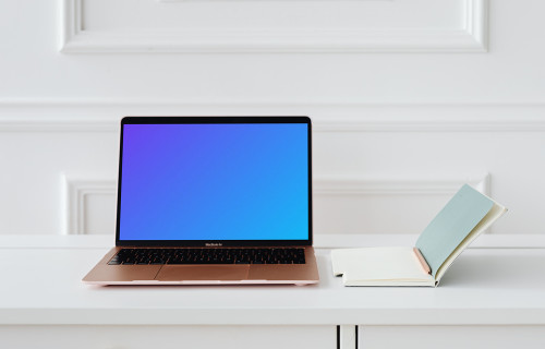 MacBook Air mockup on a table beside a notepad and a pencil