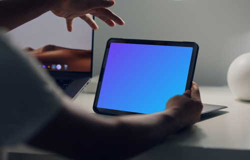 Male hands holding an iPad mockup stood on a table