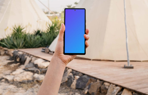 Pixel 6 mockup held by a user at an outdoor campsite