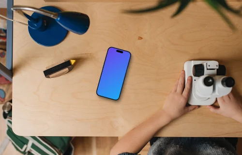 Smartphone mockup on wooden desk with kids' hands and toys