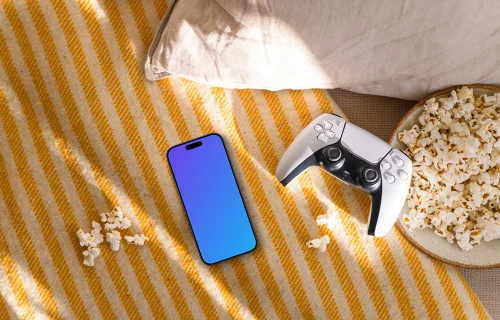 Smartphone mockup with gaming controller and snacks on cozy sofa