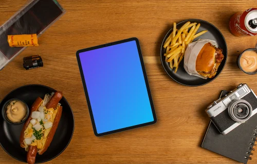 Tablet mockup between plates with hot-dogs