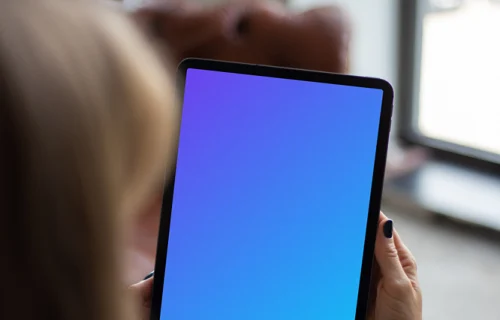 Tablet mockup held by user beside a window