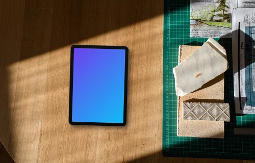 Tablet mockup on architect's workspace with blueprints and materials