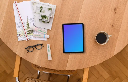 Tablet mockup with architectural plans on a wooden table